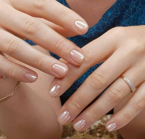Korta naglar belagd fast genomskinlig färg appliceras ovanpå vtirka pärla.